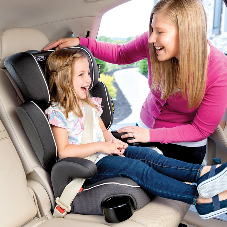 Mom smiling and adjusting the headrest for little girl sitting in Graco Assure car seat
