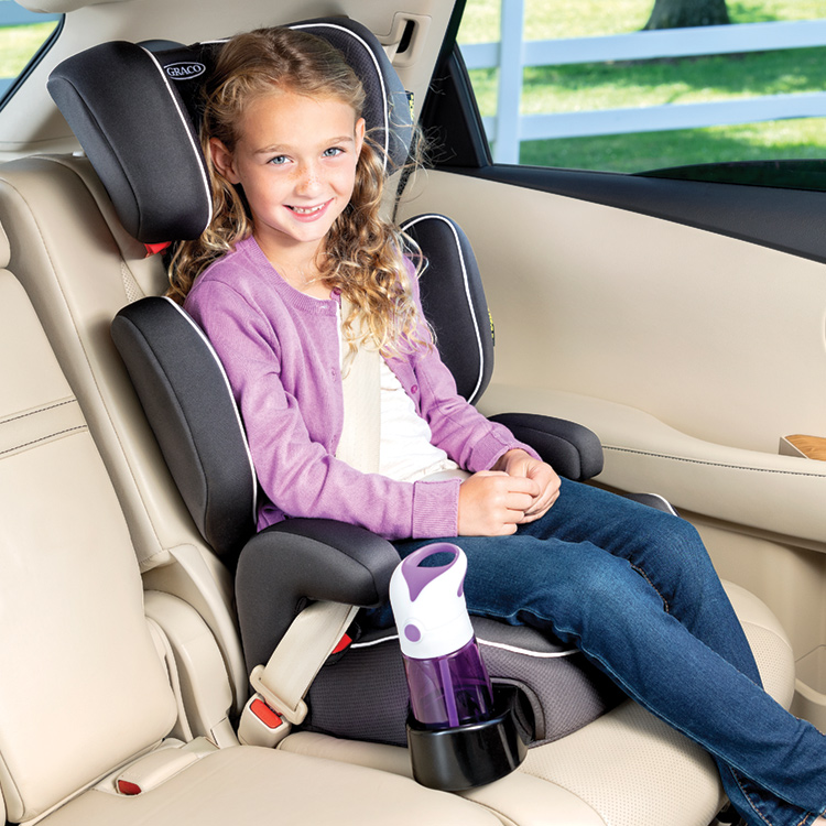 Little girl smiling and sitting in Graco Assure car seat with a water bottle in the cupholder