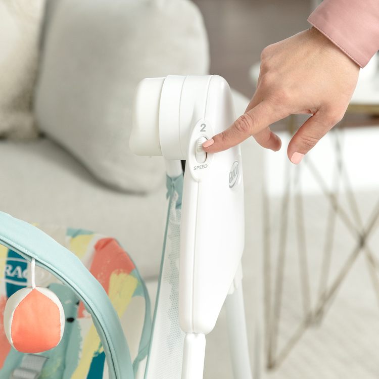 Frau reguliert die Geschwindigkeit der elektrischen Babyschaukel Graco Baby Delight