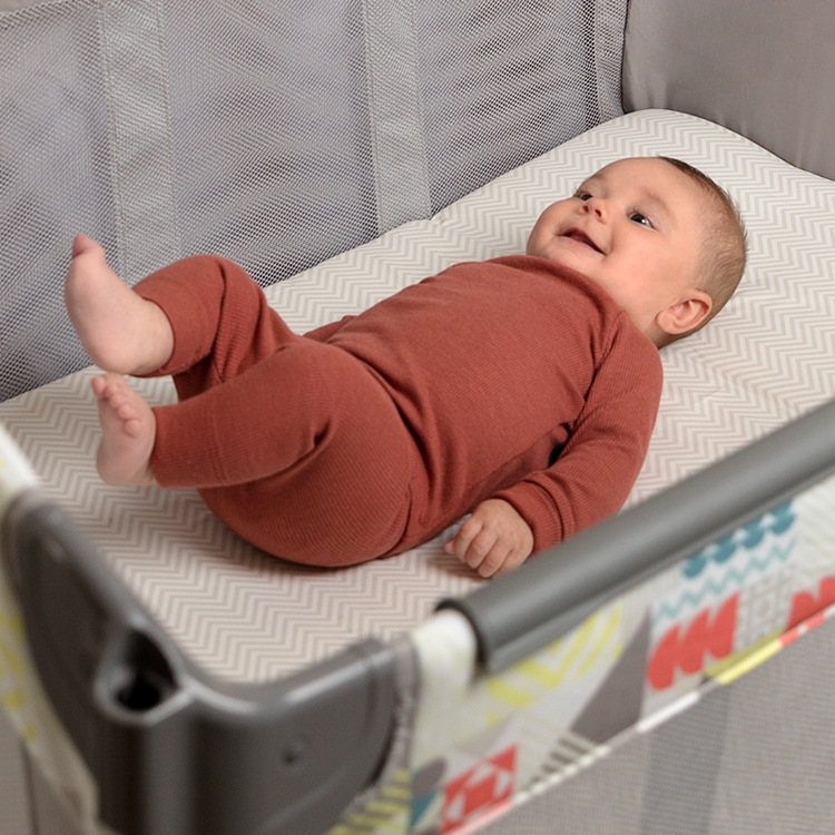 Baby liegt im abnehmbaren Neugeboreneneinhang des Reisebetts Graco Contour® Electra