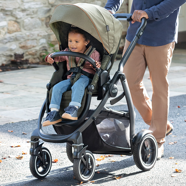 Dad pushing Graco® Evo® XT as little girl rides in the pushchair 
