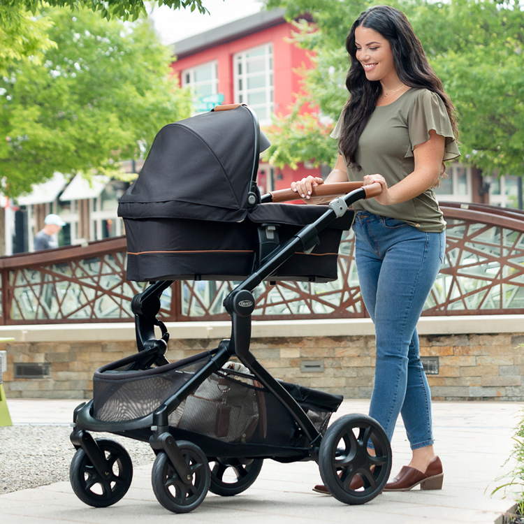Mum pushing Graco Near2Me Elite pushchair while her baby is in Near2Me Elite carrycot that is attached to pushchair frame