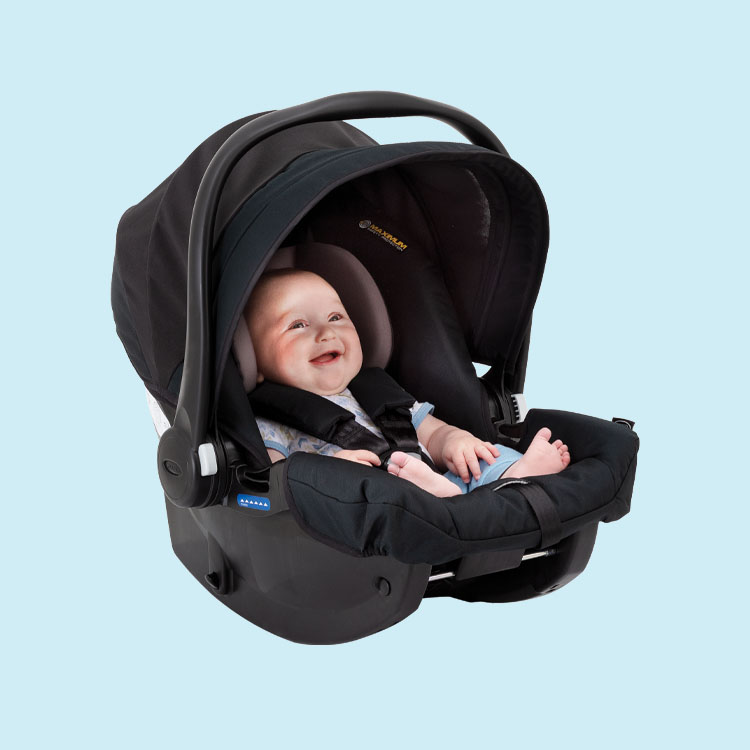 Happy baby sitting in Graco SnugEssentials i-Size car seat on blue background.