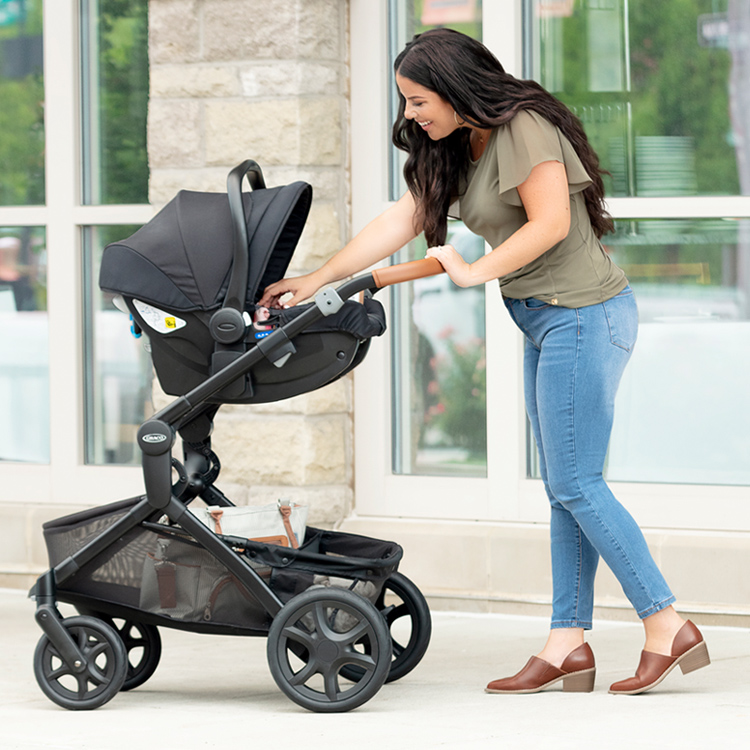 Woman pushing baby in stroller that's compatible with Graco SnugEssentials car seat